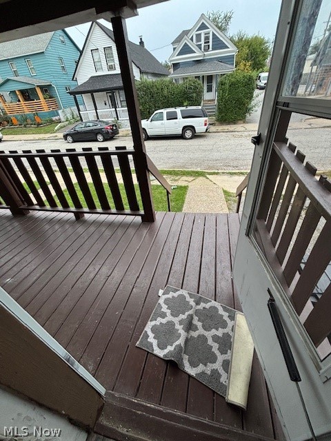 Front porch with dark wood decking and railings overlooking a residential street.