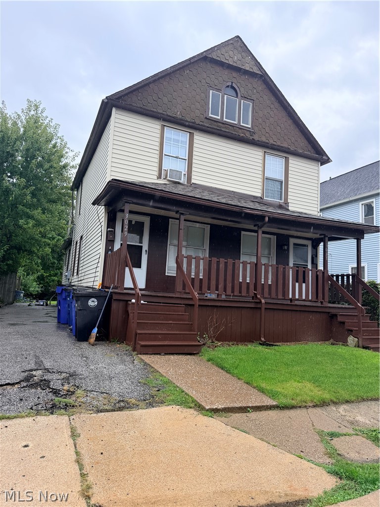 Two-story house with a steep shingled roof, dark brown porch, and front steps.