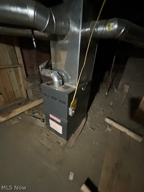 Basement furnace with exposed ductwork and unfinished floor.