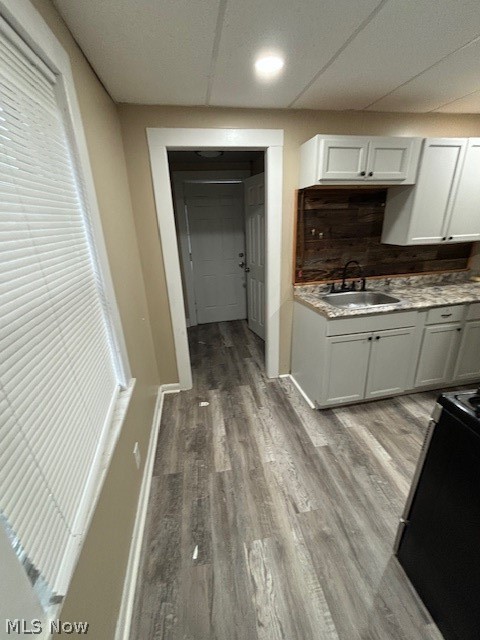 Kitchen with white cabinets, a dark wood backsplash, and gray plank flooring.