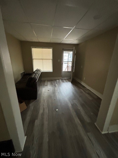 Living room with dark wood-look flooring, a sofa, and a window beside an exterior door.