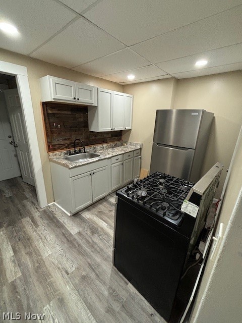 Kitchen with gray cabinets, stainless steel refrigerator, and black range.