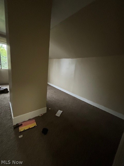 Carpeted interior with beige walls, a dividing wall, and a window.