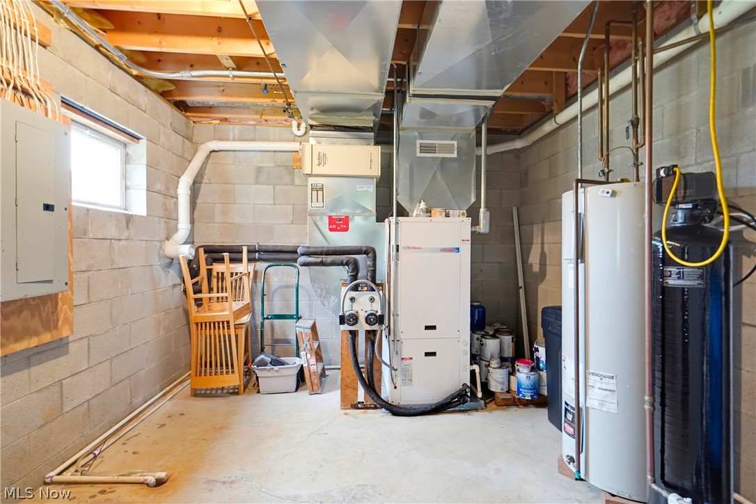Basement utility room with exposed ceiling joists, HVAC equipment, ductwork, and a water heater.