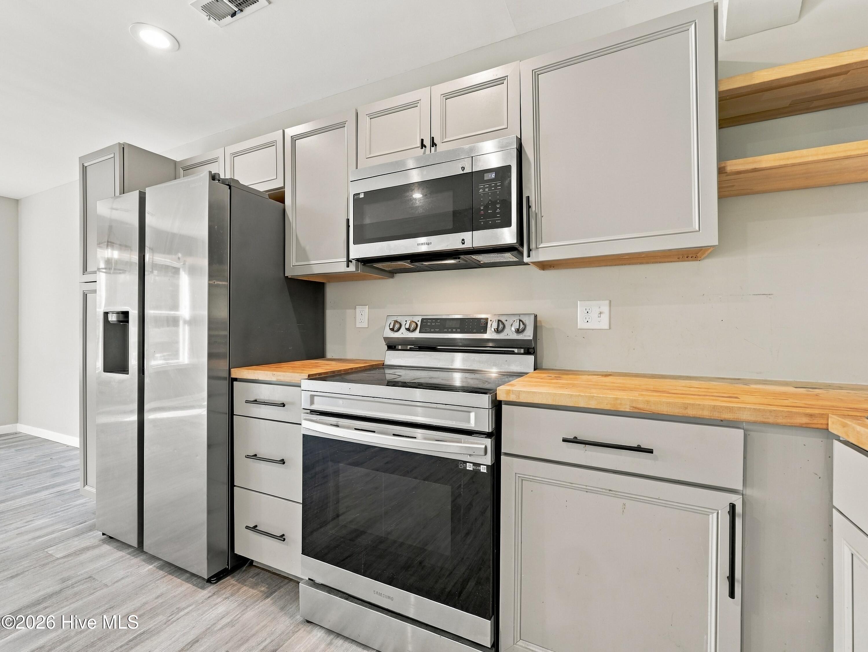 Kitchen with gray cabinets, butcher-block counters, and stainless steel appliances.