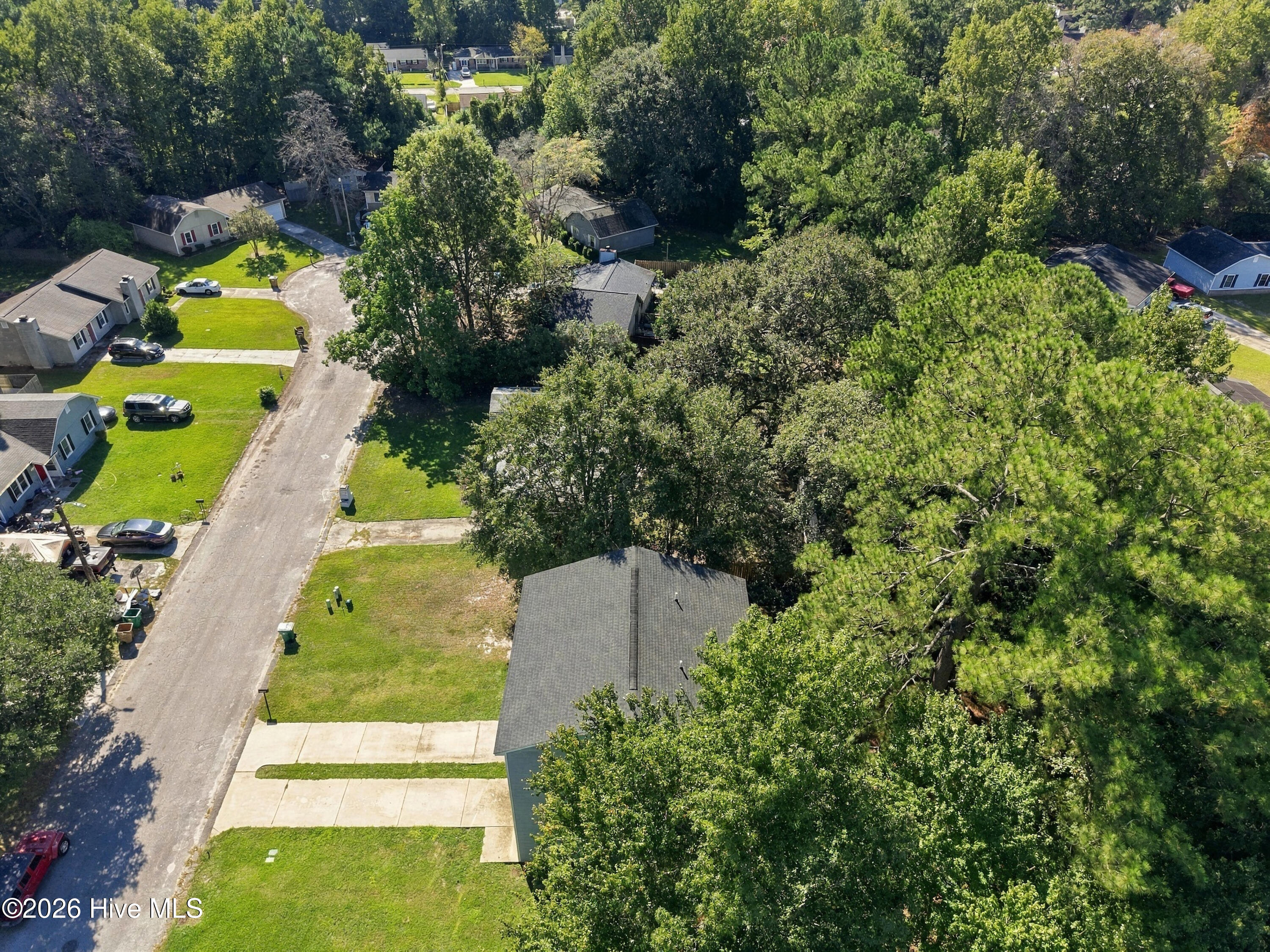 Aerial view of a home lot on a tree-lined residential street.