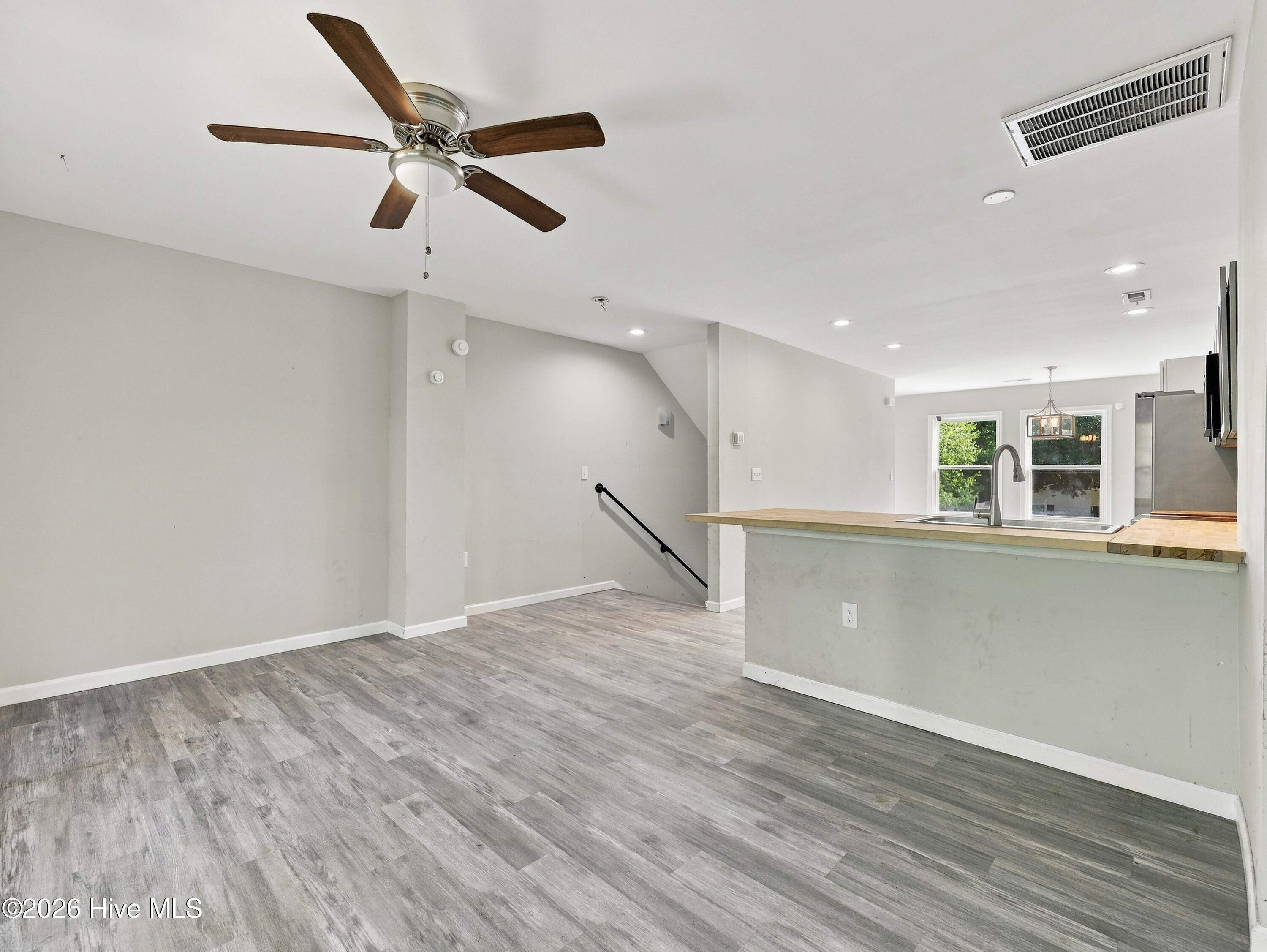 Open-plan kitchen and dining area with a wood-topped breakfast bar and gray plank flooring.