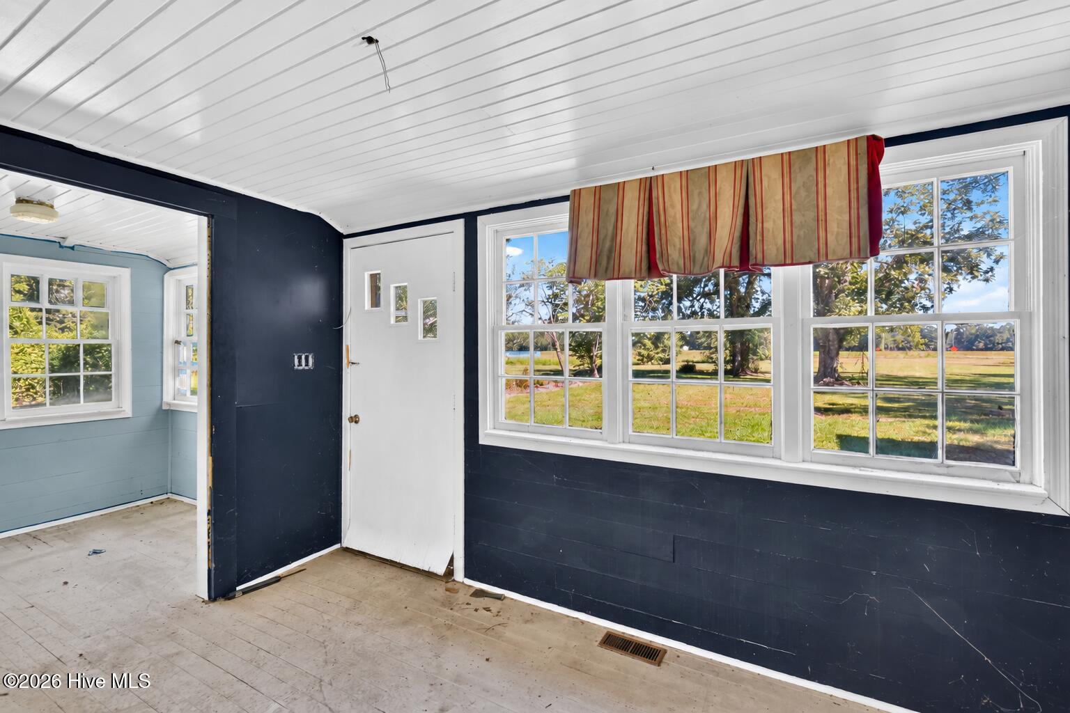 Vacant room with large windows overlooking a grassy yard and contrasting navy and pale blue walls.
