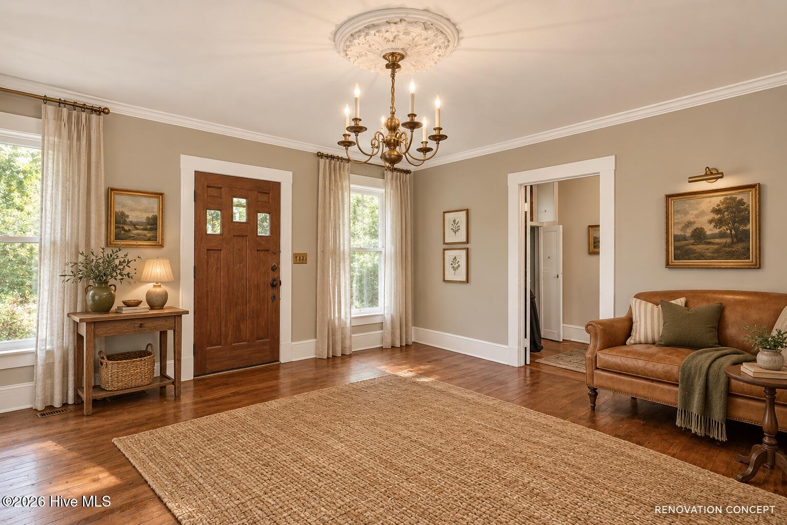 Furnished entryway with a carved wood front door, chandelier, and leather sofa.