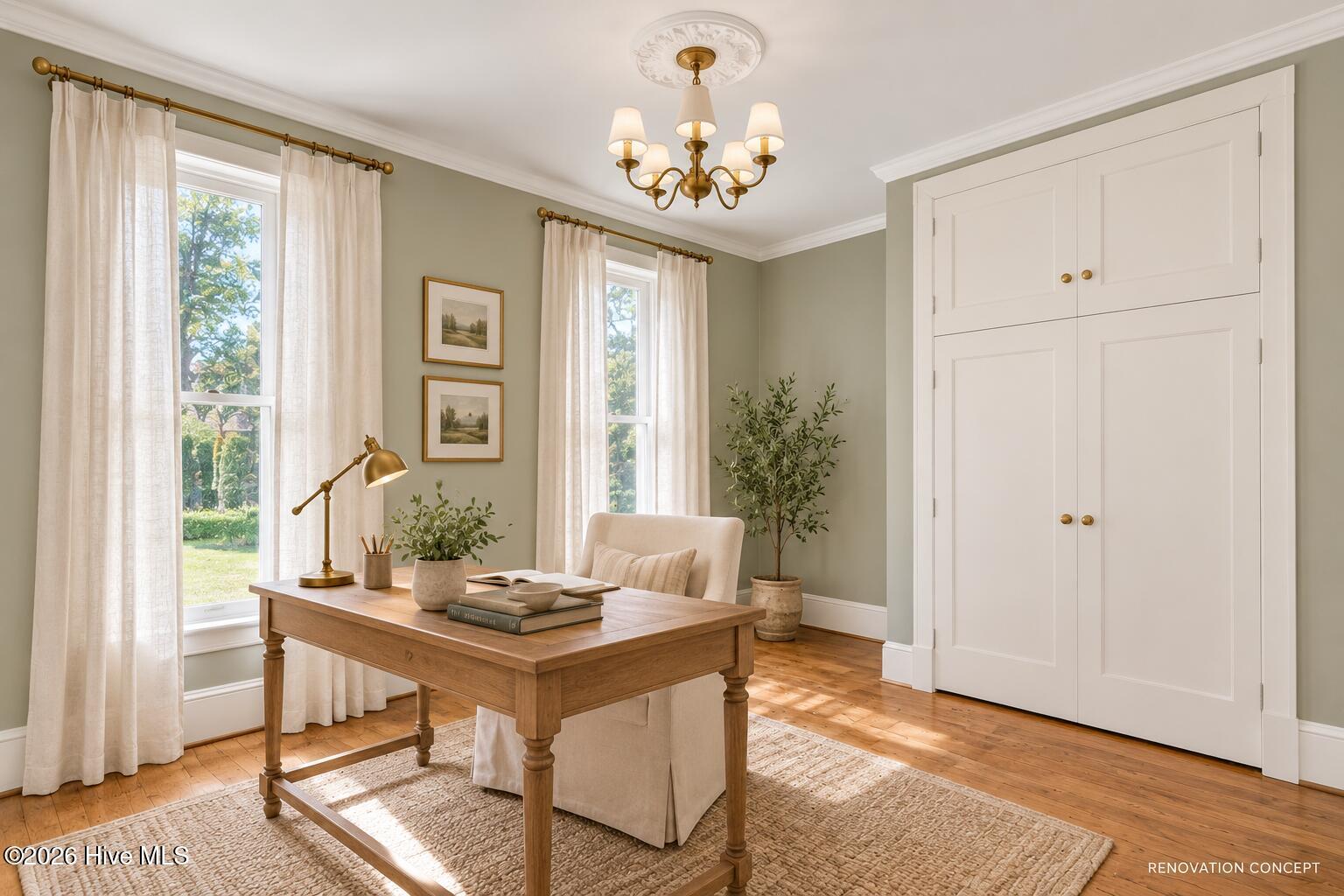 Staged home office with a wooden desk, built-in cabinets, and tall curtained windows.