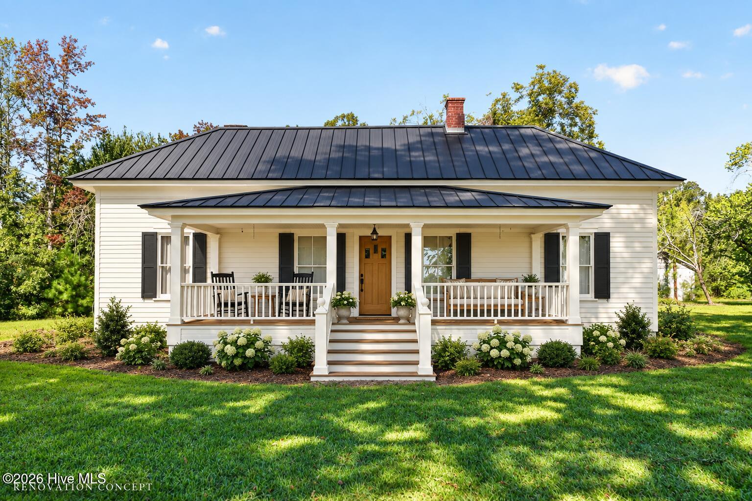 White farmhouse with a dark metal roof, broad covered porch, wooden front door, and landscaped lawn.