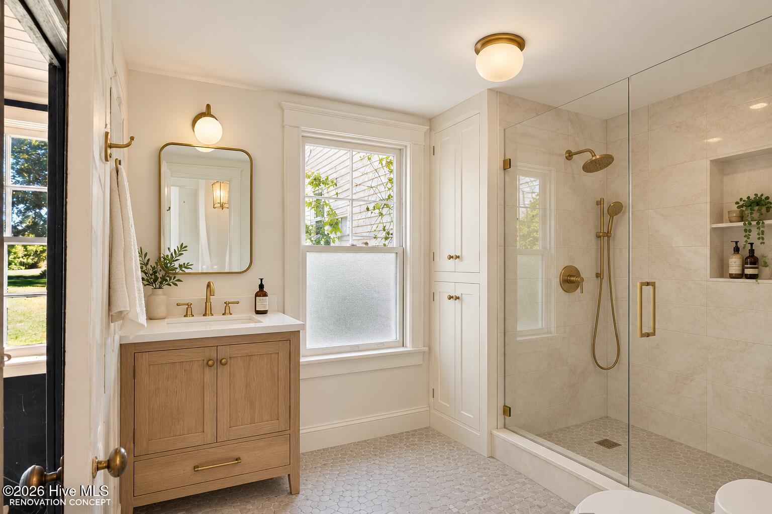 Bathroom with oak vanity, brass fixtures, and a glass-enclosed tiled shower.