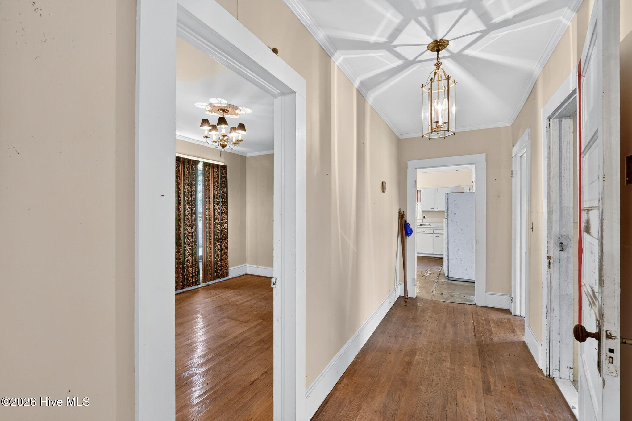 Hallway with hardwood floors and a brass lantern, opening toward a kitchen.