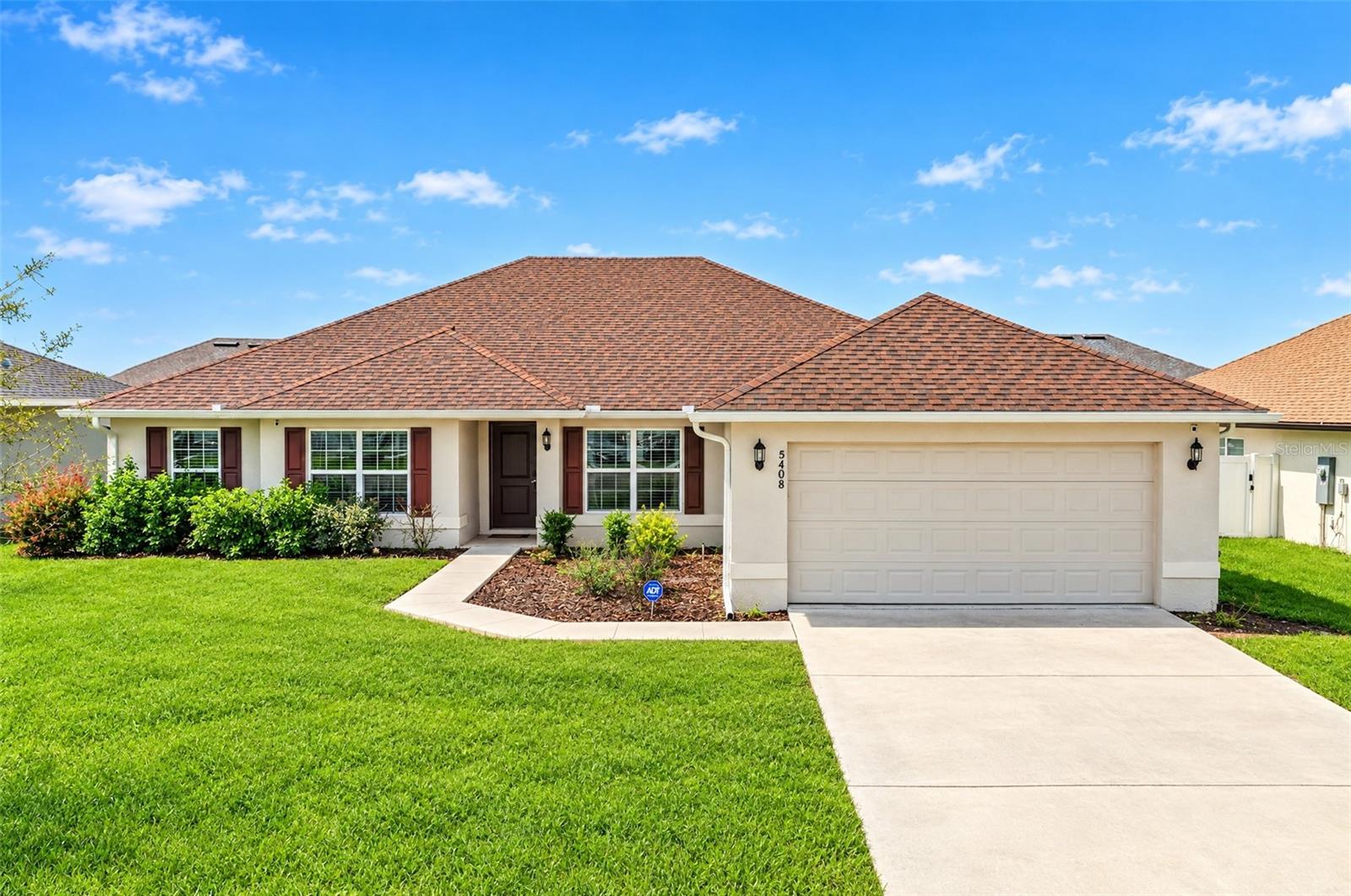 Single-story cream house with a broad shingle roof, two-car garage, and landscaped front lawn.