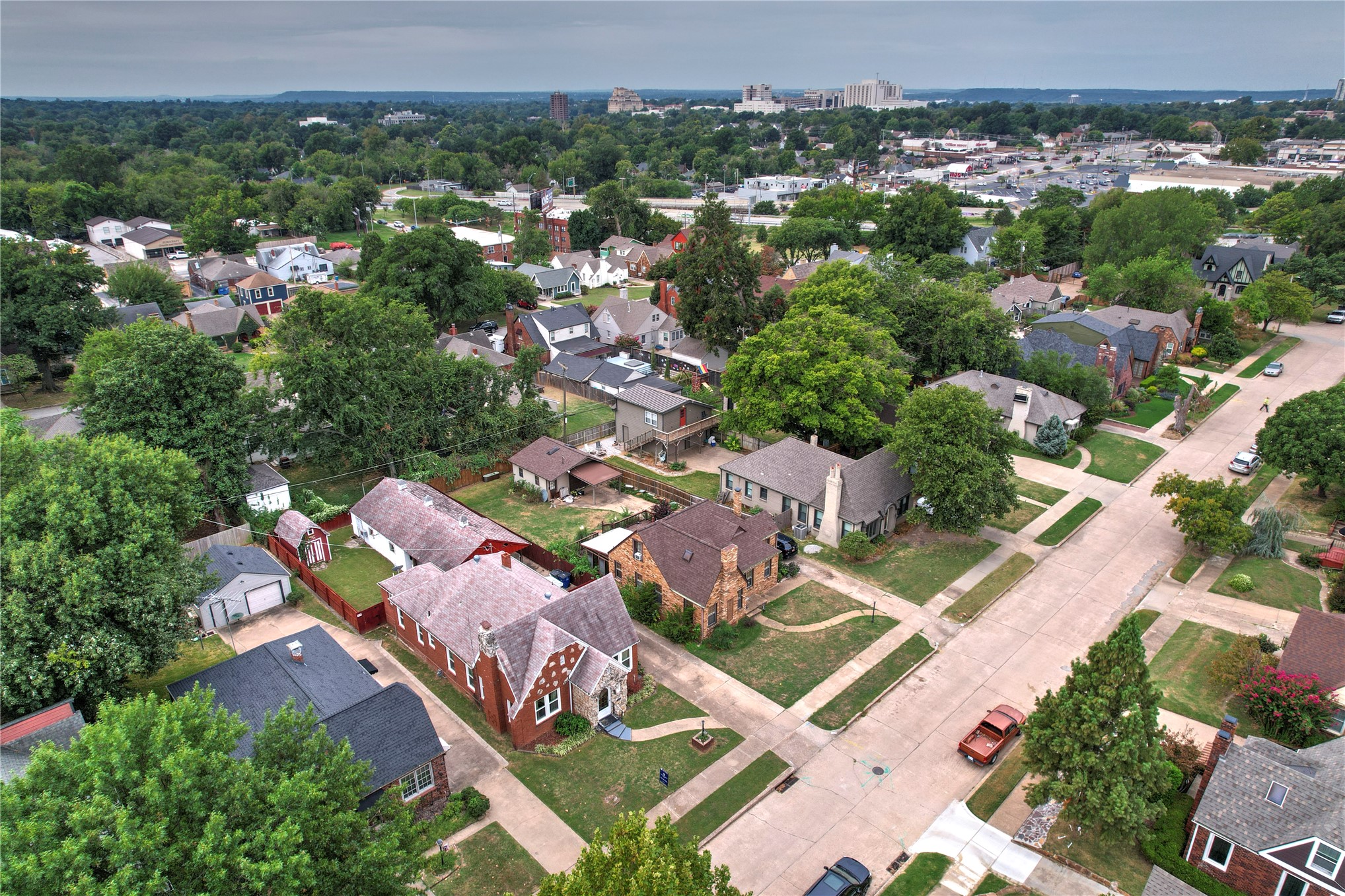 Aerial view of a leafy Tulsa neighborhood with homes, residential streets, and the distant skyline.