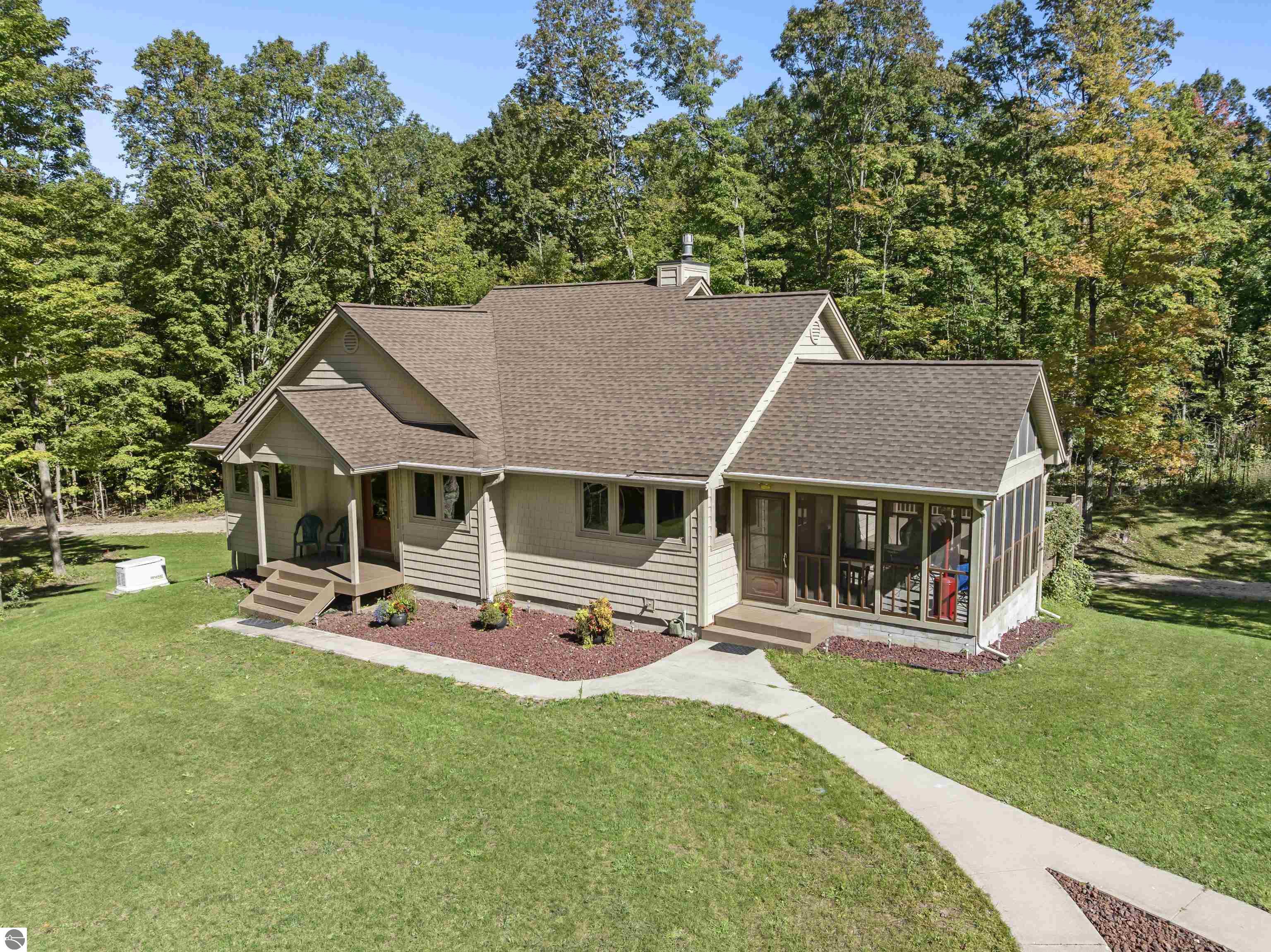 Beige home with a large screened porch, curved walkway, and wooded surroundings.