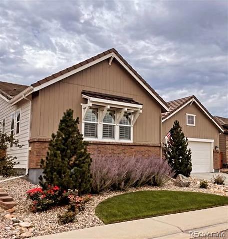 Two-story tan-and-brick house with an attached garage and landscaped front yard.