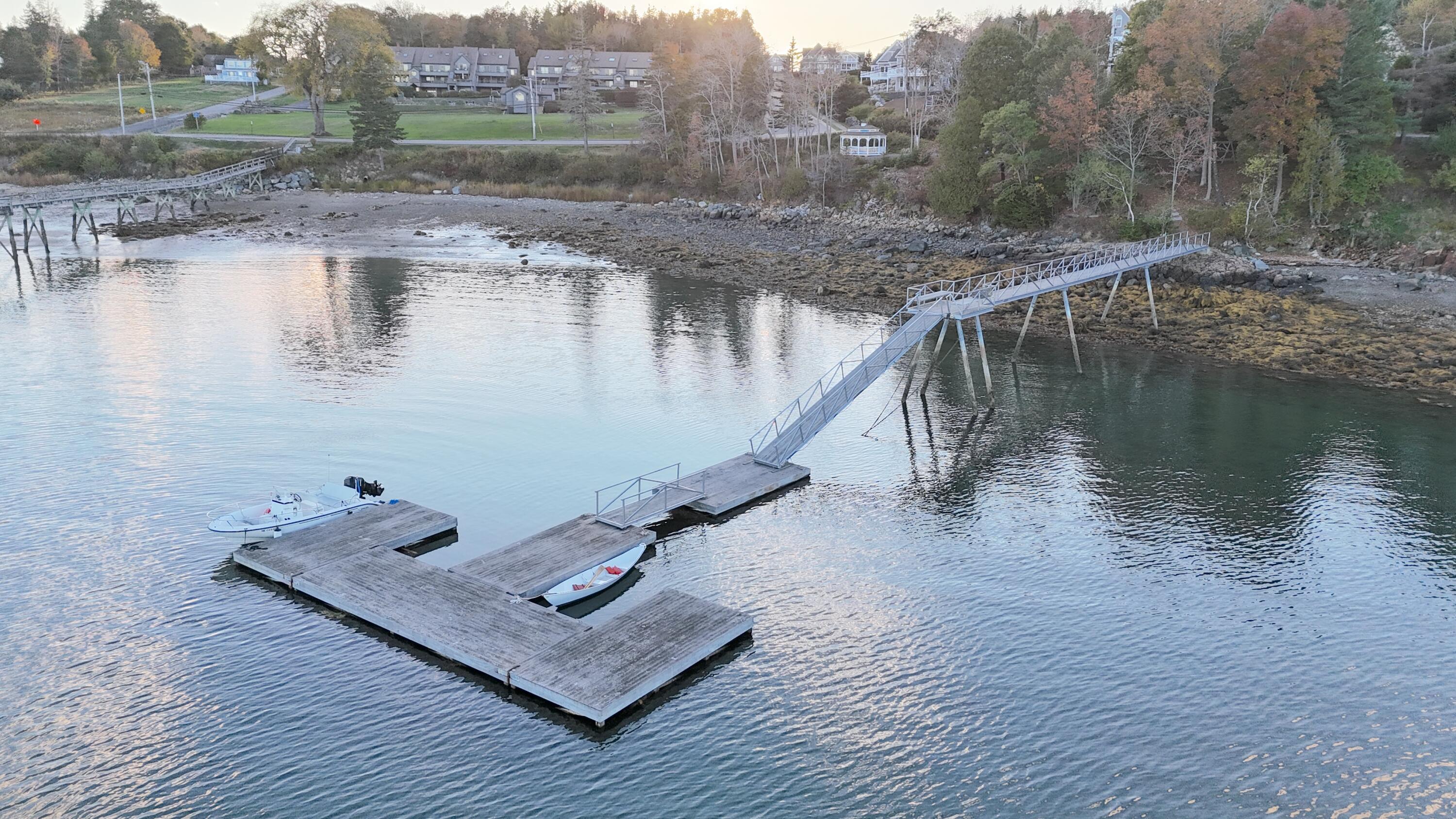 Aerial view of a waterfront dock with a long gangway and two small boats.