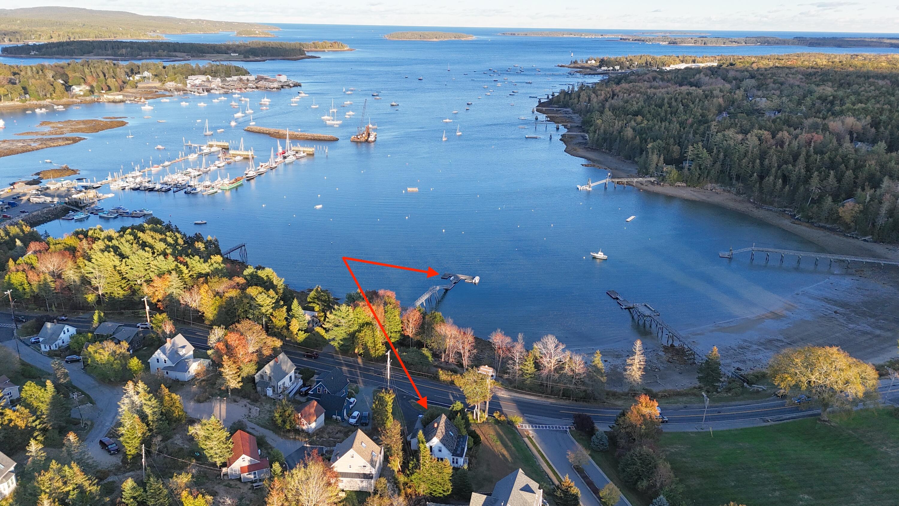 Aerial view of a waterfront home and dock beside a harbor, marked by red arrows.