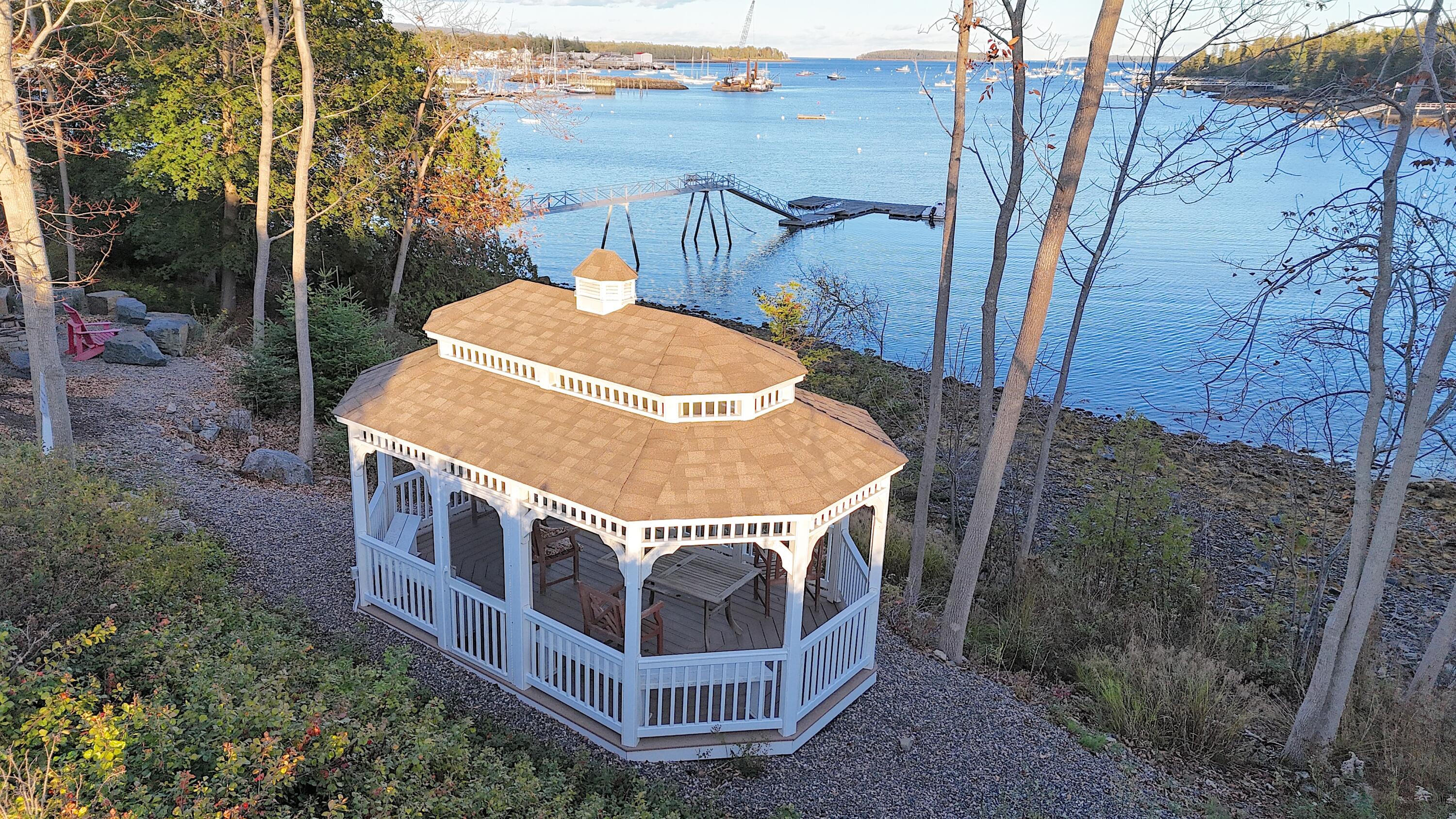 White octagonal gazebo beside a harbor, with a dock extending over the water.
