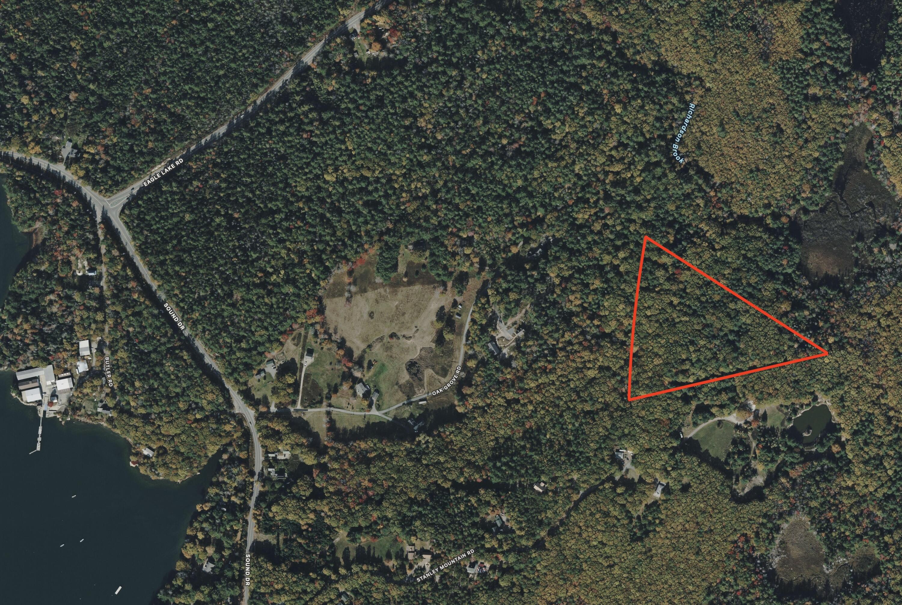 Aerial view of a wooded parcel outlined in red near Oak Grove Road, with a lake and brook nearby.