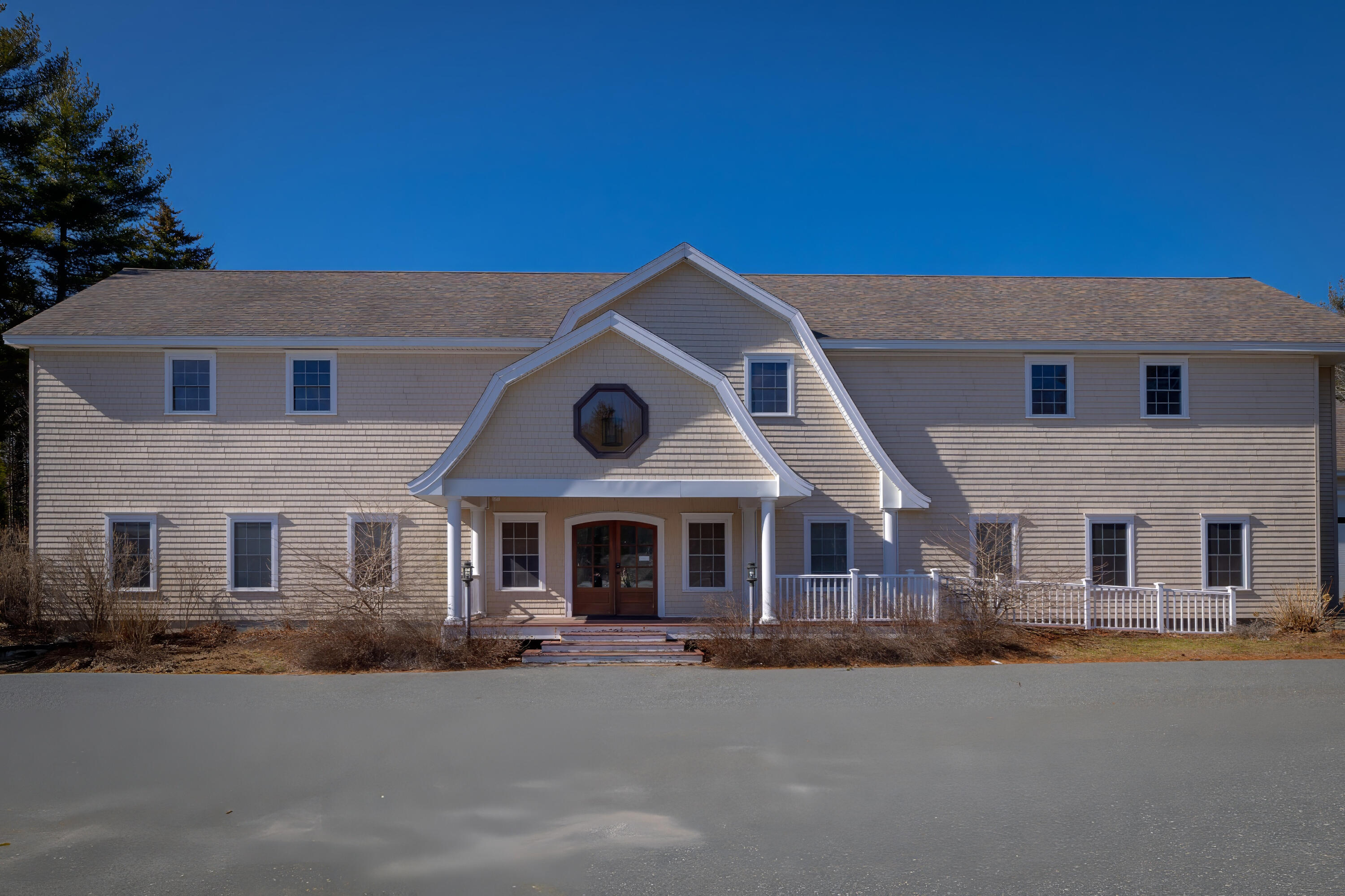 Two-story shingle-sided house with a double-gabled entrance and octagonal window above the porch.