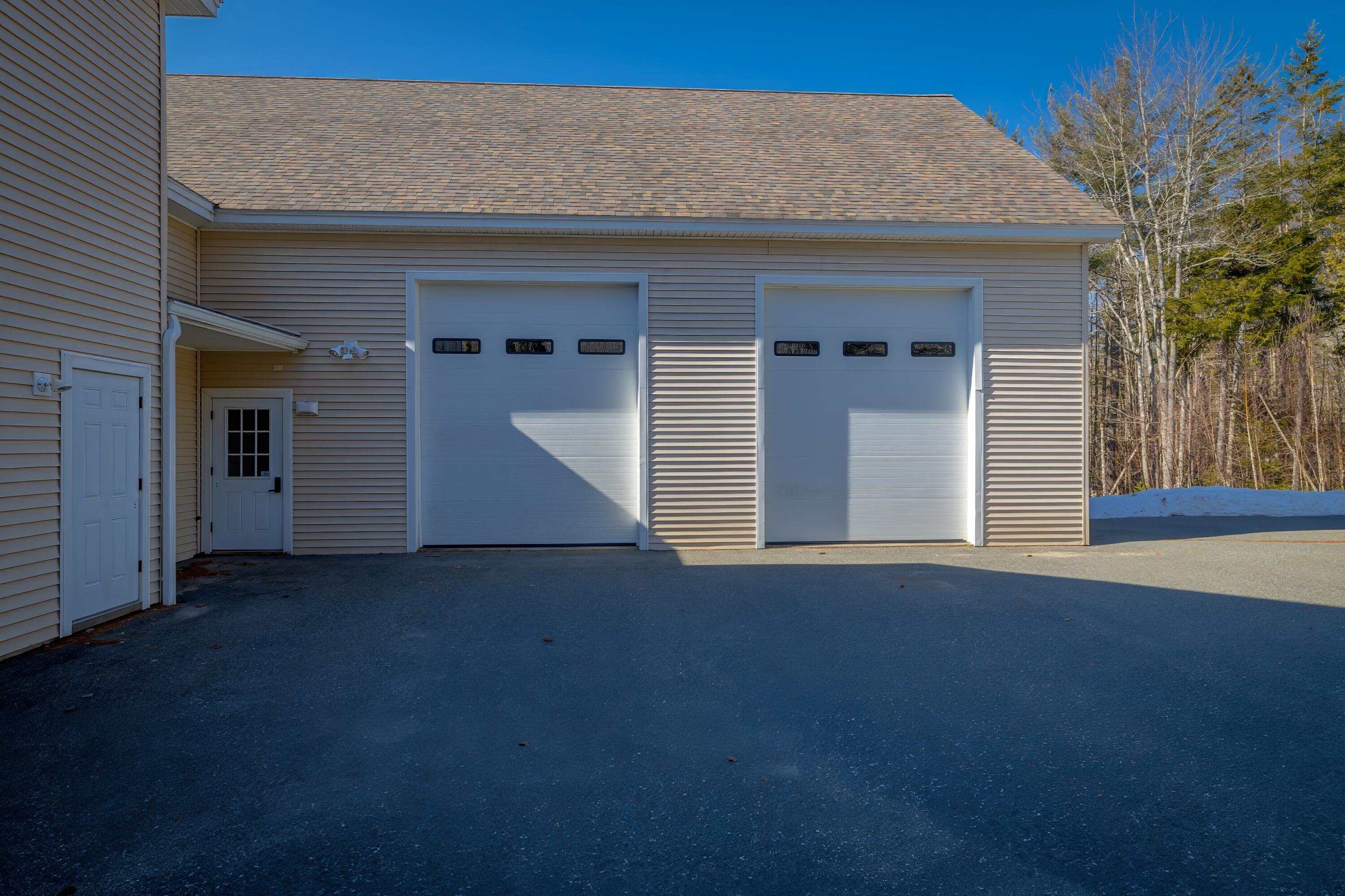 Garage exterior with two white overhead doors and a paved driveway.