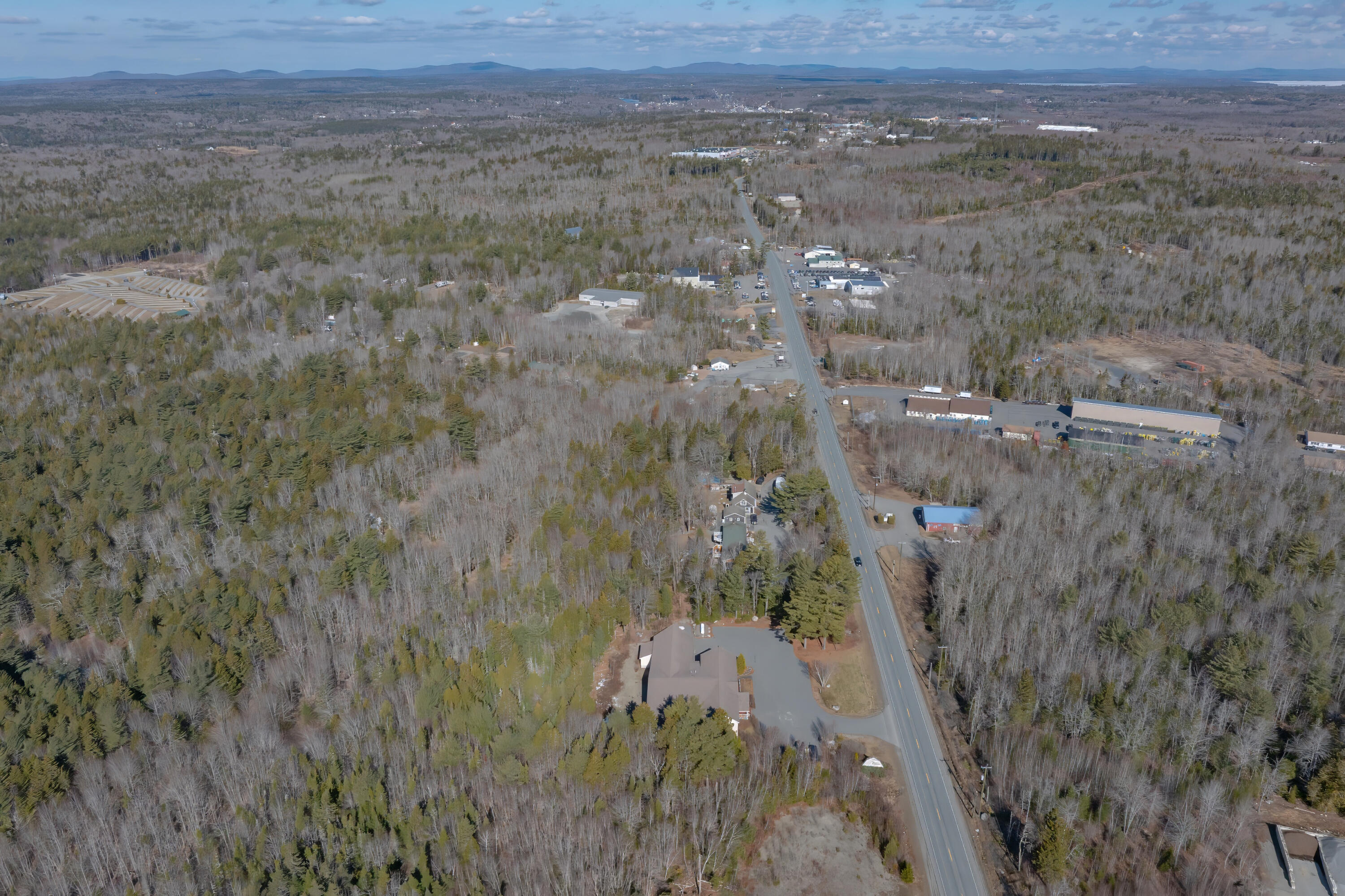 Aerial view of wooded Trenton, with Bar Harbor Road passing scattered homes and commercial buildings.