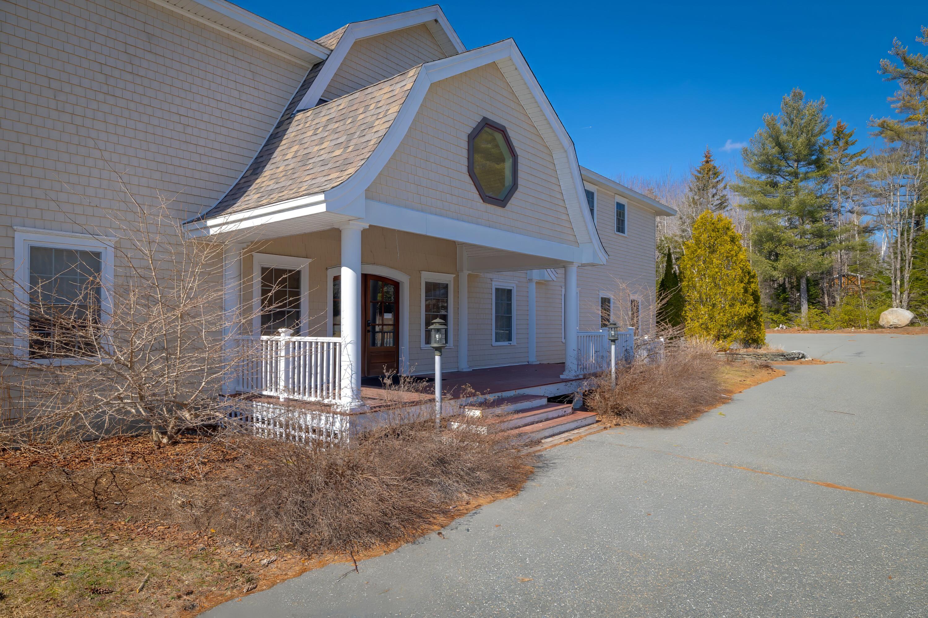 Shingle-sided house with covered porch, white columns, and an octagonal gable window.