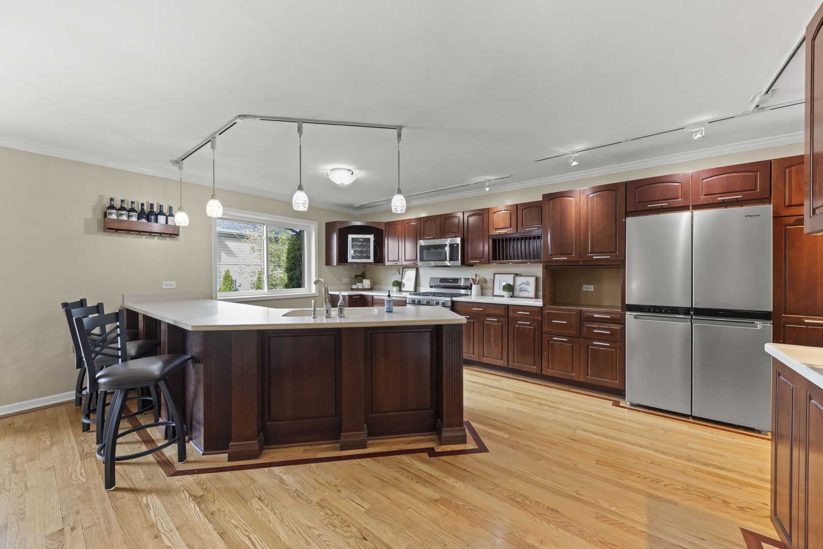 Kitchen with a large island, cherry cabinets, stainless steel appliances, and hardwood floors.
