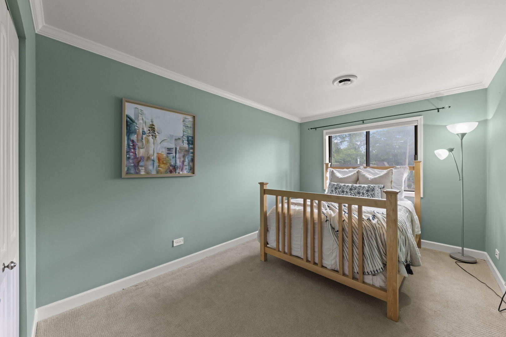 Bedroom with teal walls, a wooden bed, patterned white bedding, and a large daylight window.