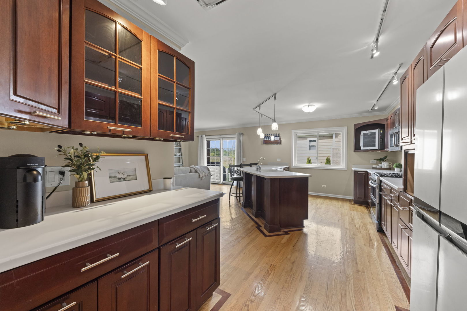 Spacious kitchen with dark wood cabinets, a large island, stainless steel appliances, and hardwood floors.
