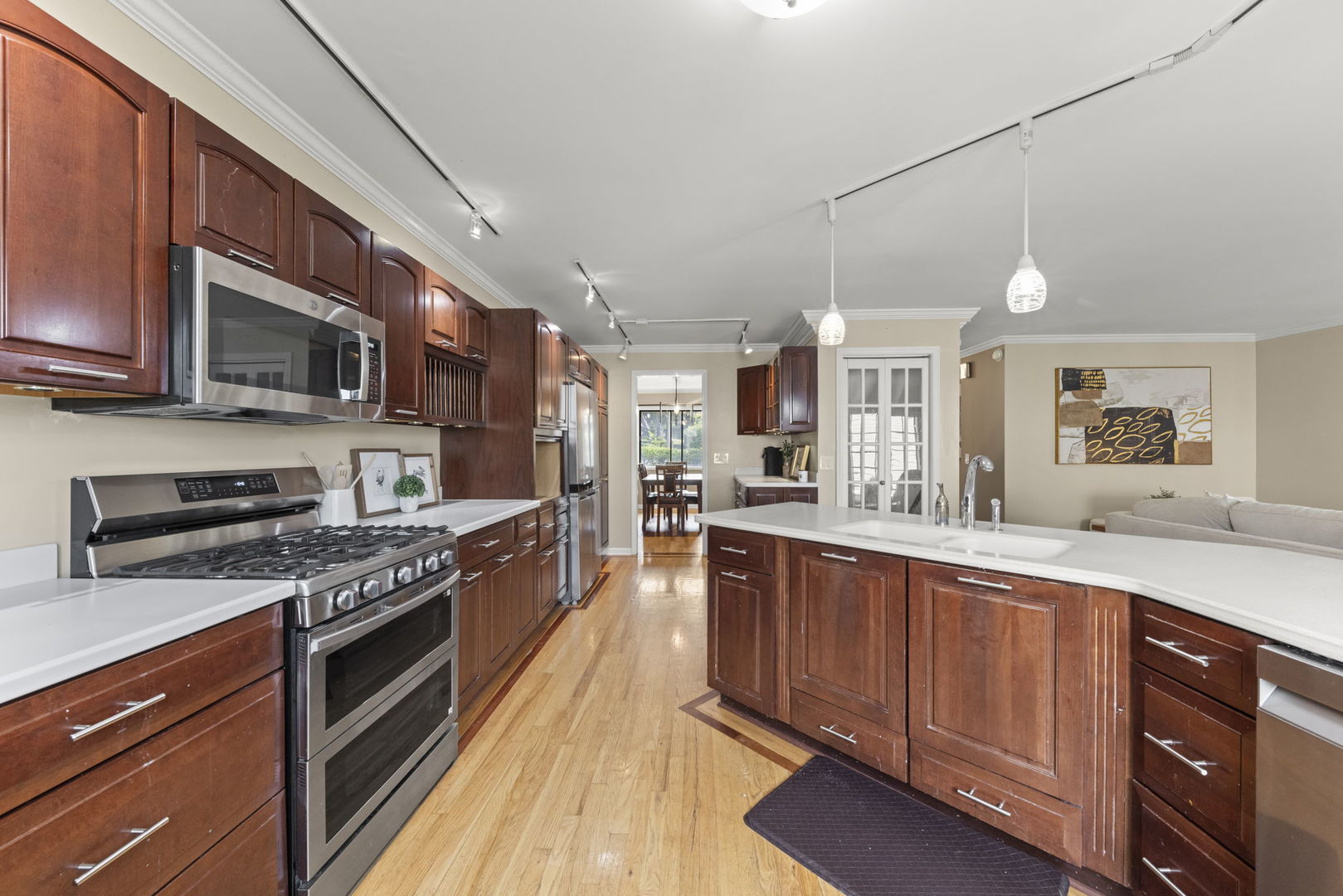 Kitchen with cherry cabinets, a large white island, stainless steel appliances, and hardwood floors.