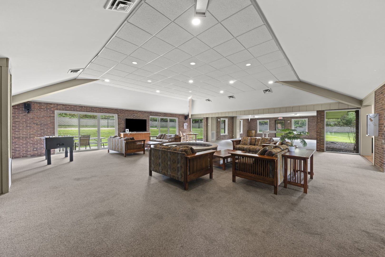 Furnished recreation room with brick walls, a pool table, and large windows.
