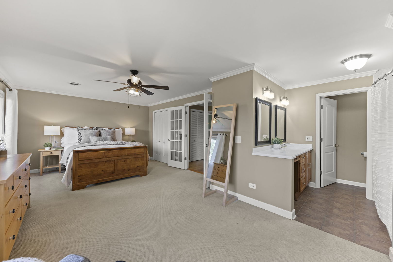 Bedroom with a wooden bed, ceiling fan, and adjoining bathroom vanity.