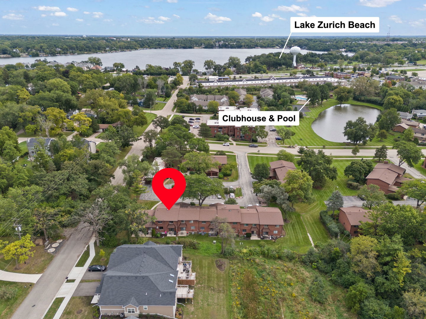 Aerial view of the marked townhomes, with a clubhouse, pool, pond, and Lake Zurich Beach in the distance.