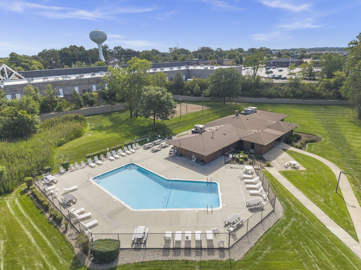 Outdoor community pool with lounge chairs, a clubhouse, and landscaped grounds.
