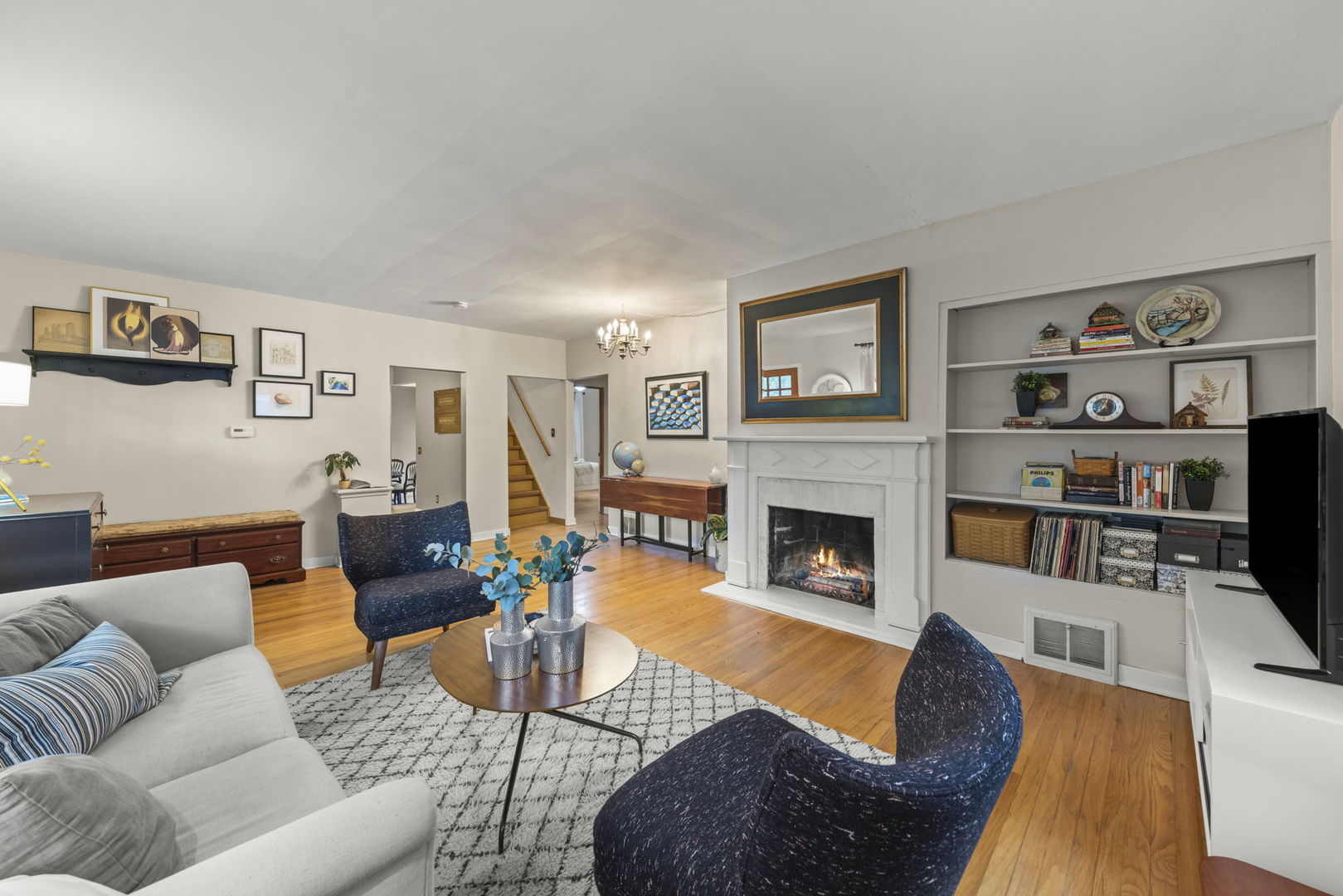 Furnished living room with a white fireplace, built-in shelves, and hardwood floors.