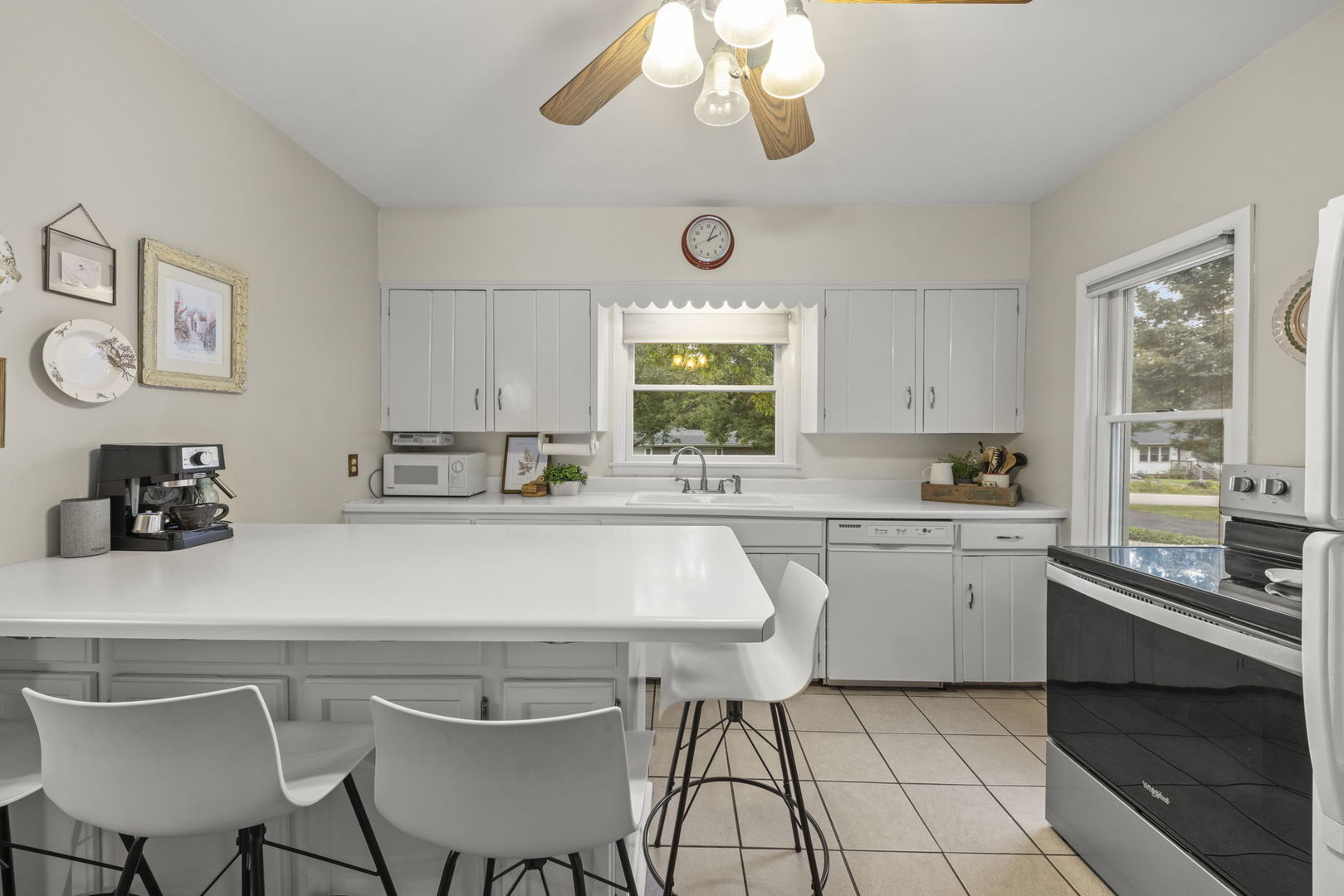 Kitchen with white cabinets, a large breakfast peninsula, and stainless-steel appliances.