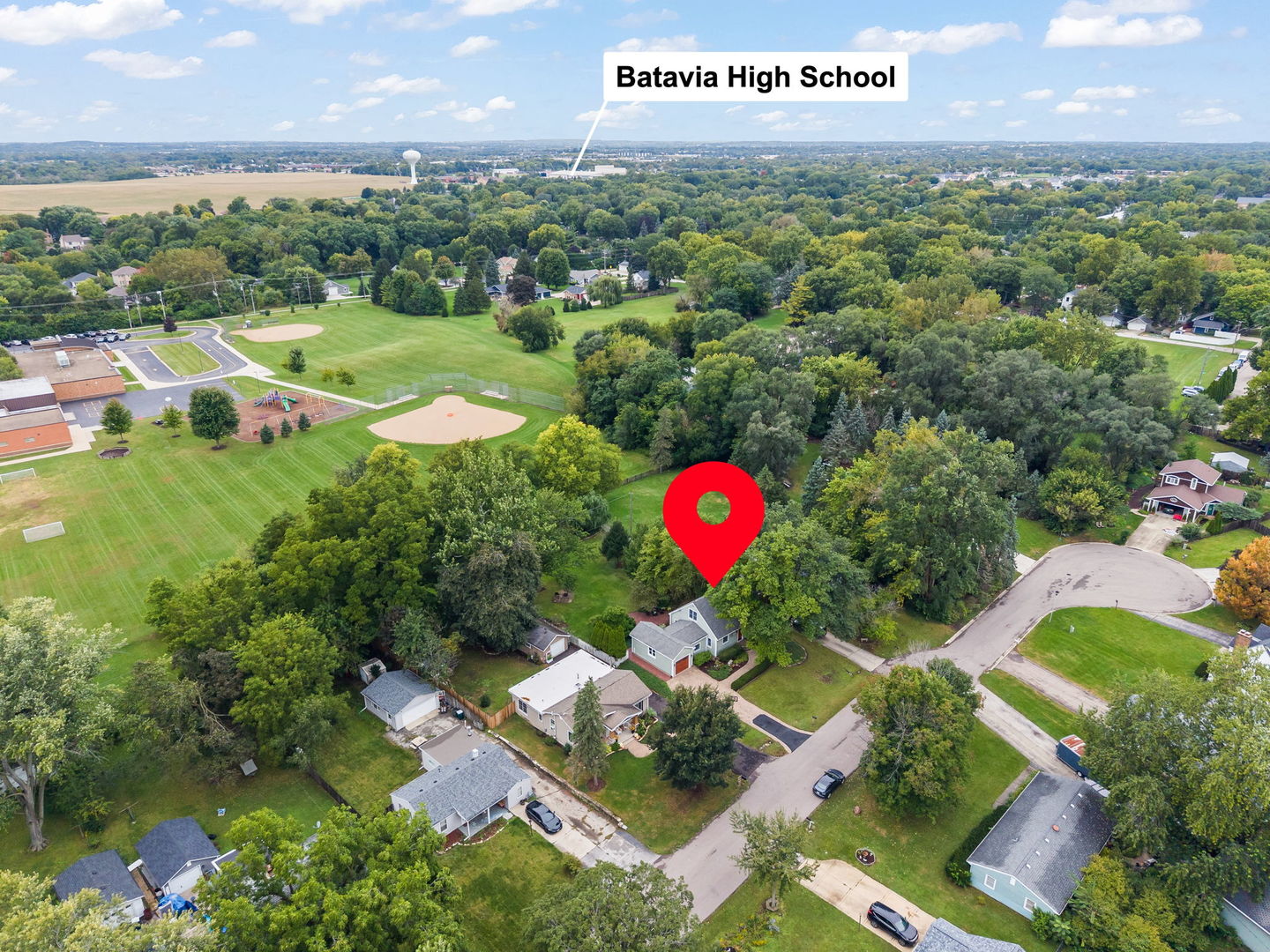Aerial view of the marked home in a leafy neighborhood, with school fields and a playground nearby.