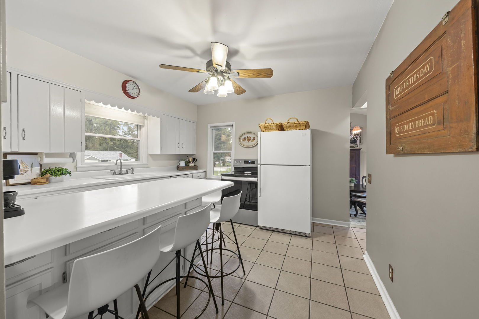 Kitchen with white cabinetry, a long breakfast bar with stools, and a white refrigerator.
