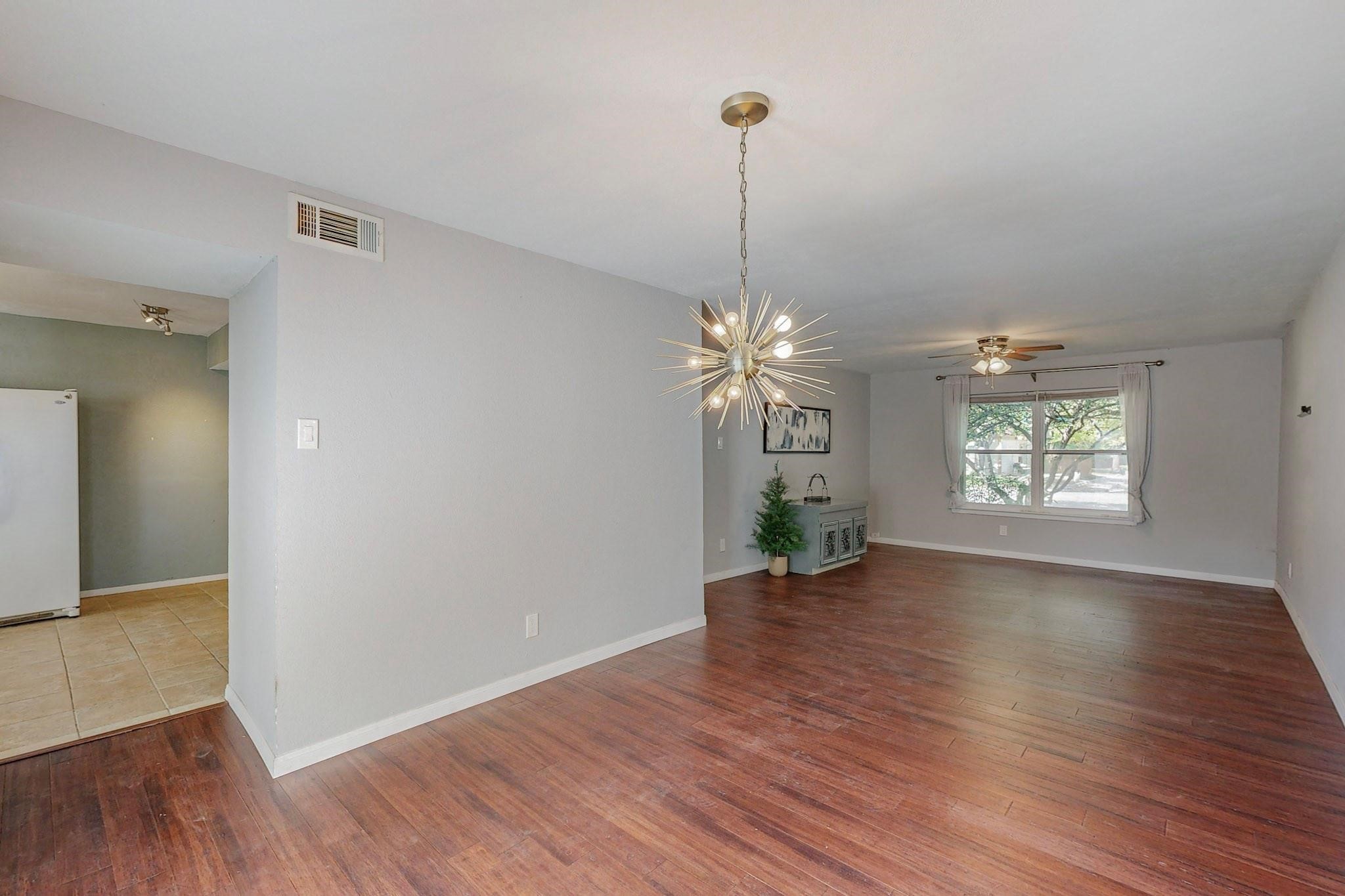Open living and dining area with hardwood floors and a striking starburst chandelier.