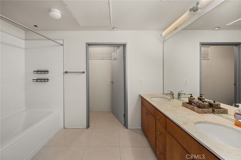 Bathroom with a bathtub and long double-sink vanity beneath a large mirror.