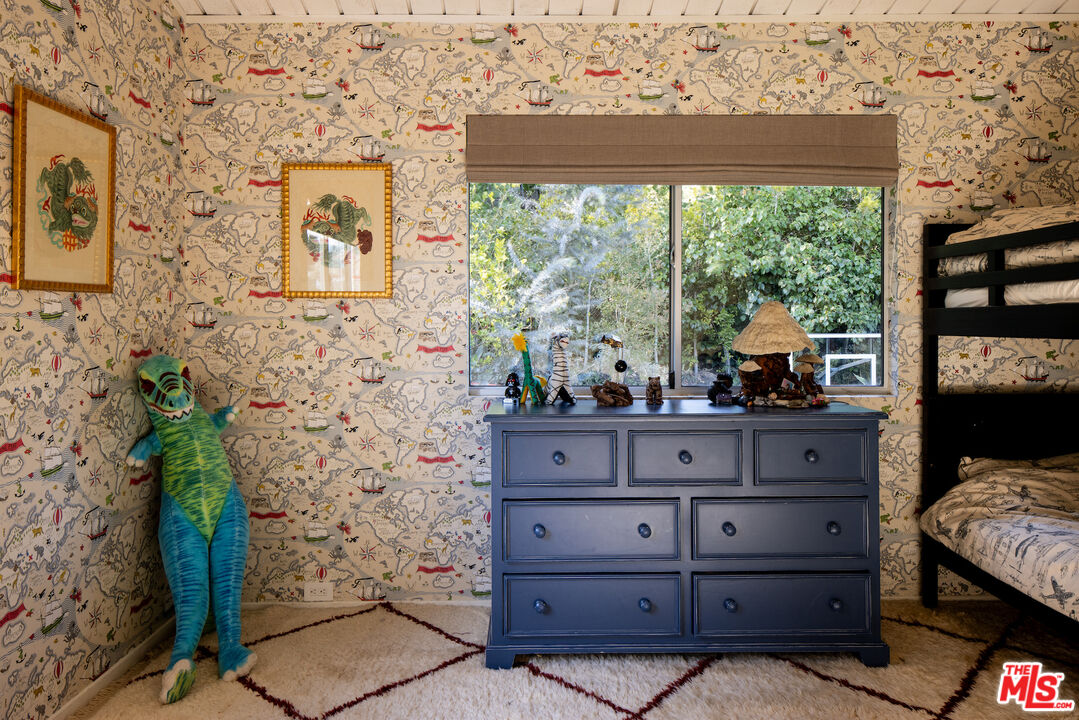 Bedroom with map-patterned wallpaper, a black bunk bed, blue dresser, and toy dinosaur.