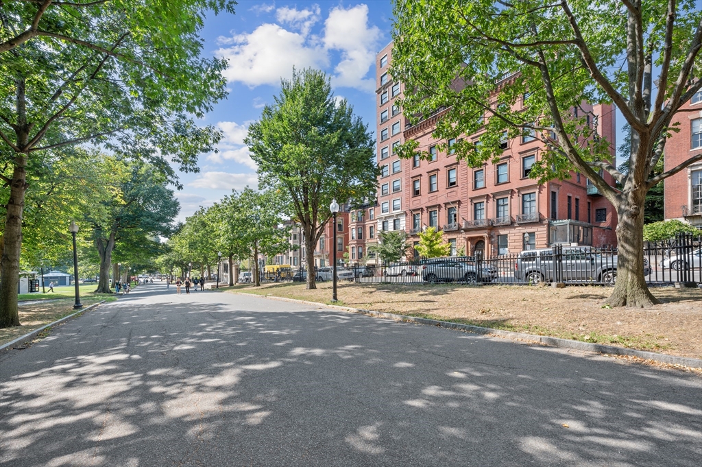 Red-brick apartment building along a tree-lined city street.