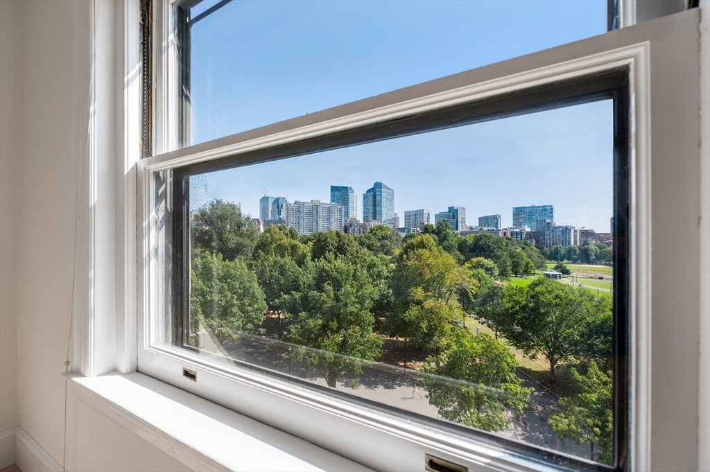 City skyline and leafy park viewed through a large apartment window.