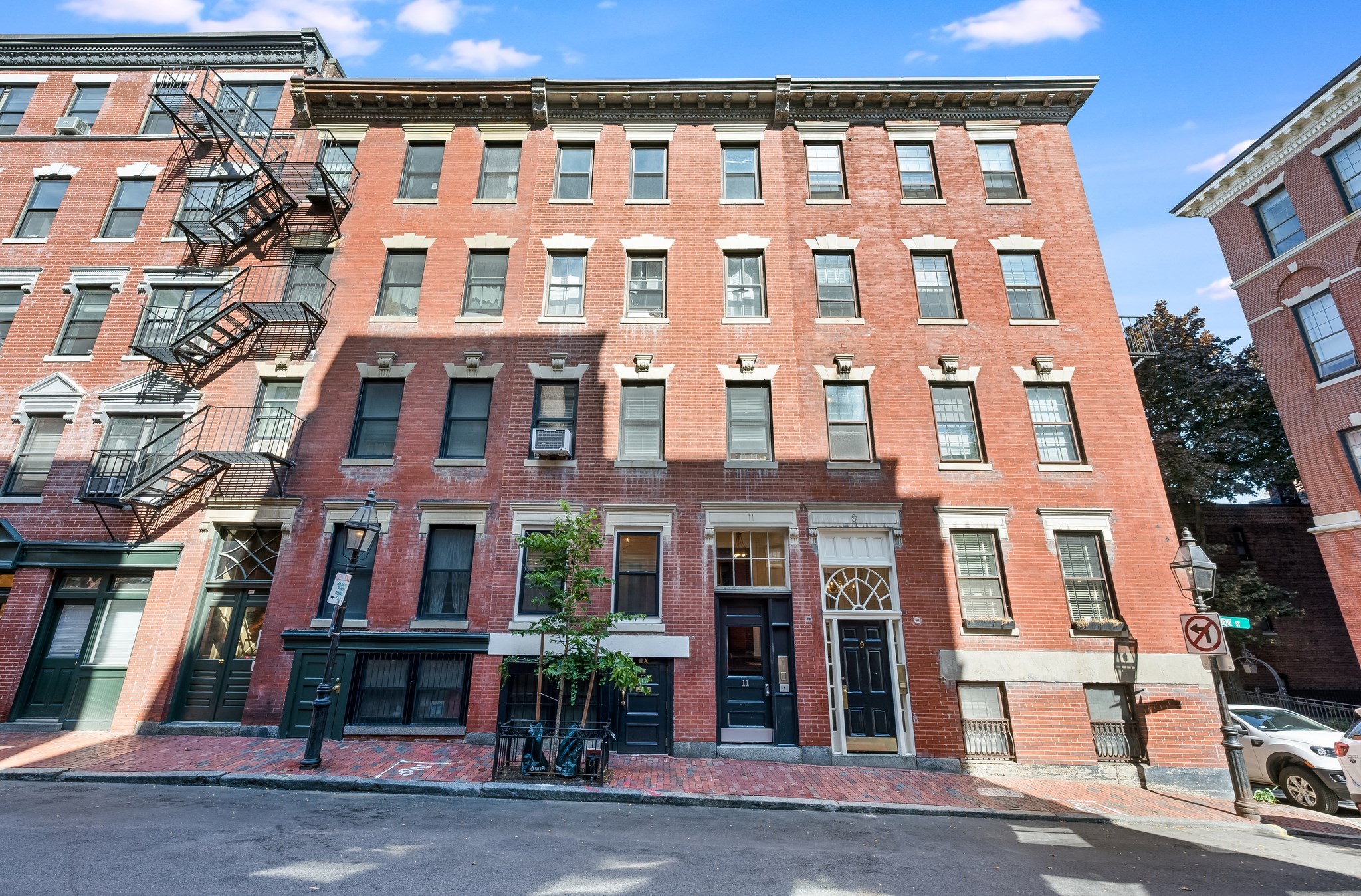 Red-brick apartment building with black fire escapes and the entrance marked 11.