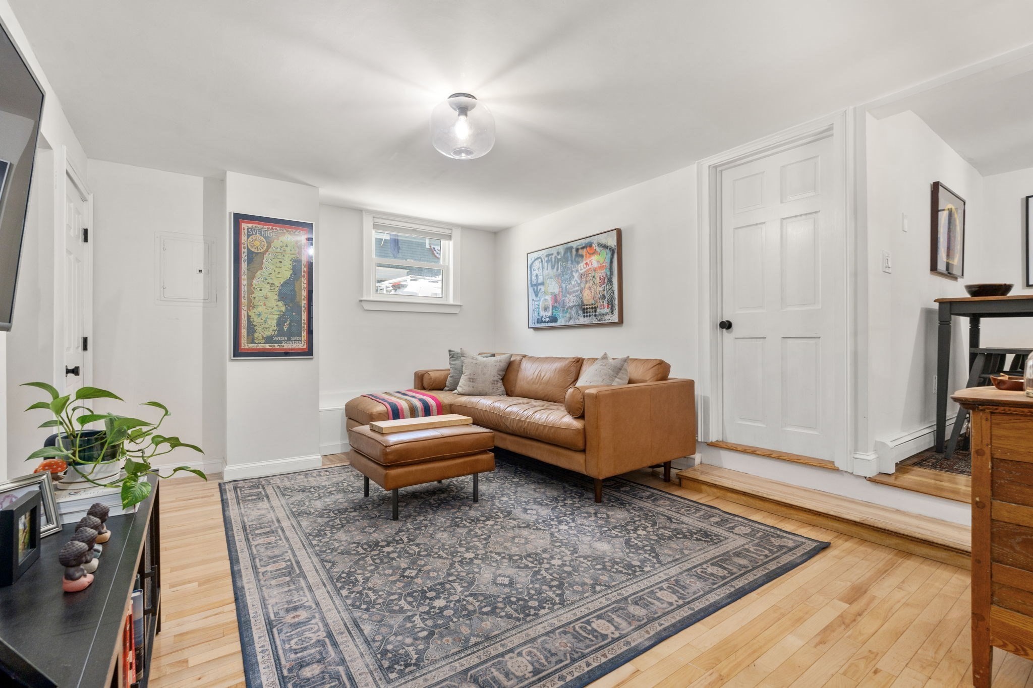 Living room with a tan leather sofa, matching ottoman, and large patterned rug.