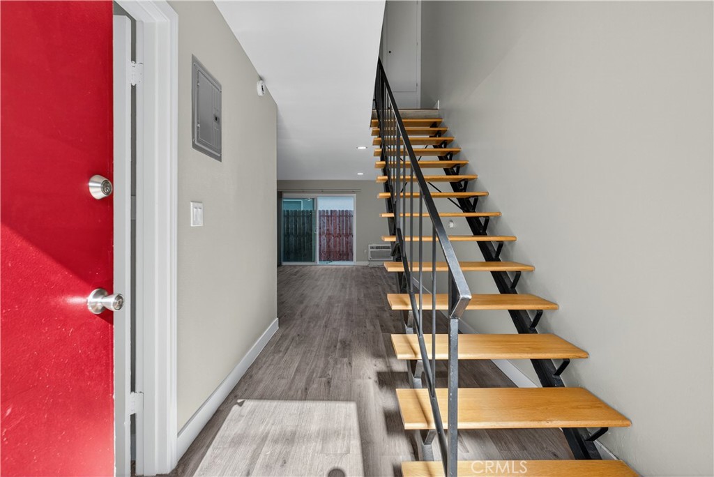 Entry hall with open wood-and-black-metal staircase and red front door.