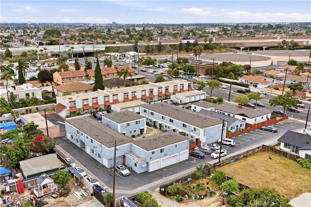 Aerial view of a blue multifamily apartment complex with parking and a freeway in the distance.
